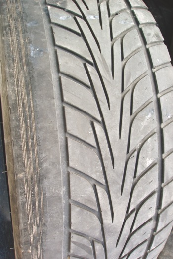 photo 3: this tire illustrates extreme camber angle wear with some feathering on the tread blocks. extreme camber wear as shown can be caused by a bent spindle.