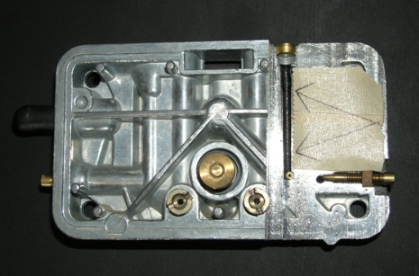 the arrows in this cutaway shot of a holley metering block (seen on the tape on right side of the block) points to the idle well, the size of the idle well helps determine how rich the off-idle air/fuel mixture will be.