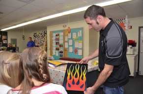 PPG painter Jason Lutton displays a flame-painted panel to Hudson School students.