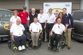 Left to right: John Scott and his wife; Penske Racing driver Joey Logano; Roger Penske, owner of Penske Racing; Al Kovach Jr., national senior vice president, Paralyzed Veterans of America; Rusty Barron, vice president of marketing, Shell Lubricants; Istavan Kapitany, president of Shell Lubricants Americas; Hank Ebert and his wife; and Penske Racing driver Brad Keselowski unveil retrofitted vehicles, donated by Pennzoil through Paralyzed Veterans of America's 